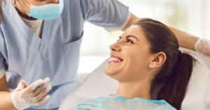 Smiling female patient receiving a dental exam from a orthodontist using instruments illustrating recovery after oral surgery in Las Vegas, NV.